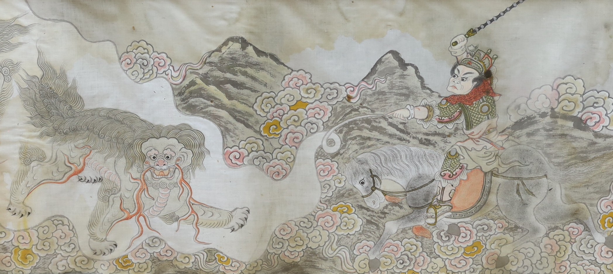 A framed Chinese silk study depicting a solider on horseback executing a dragon in stance, 49 x 104cm